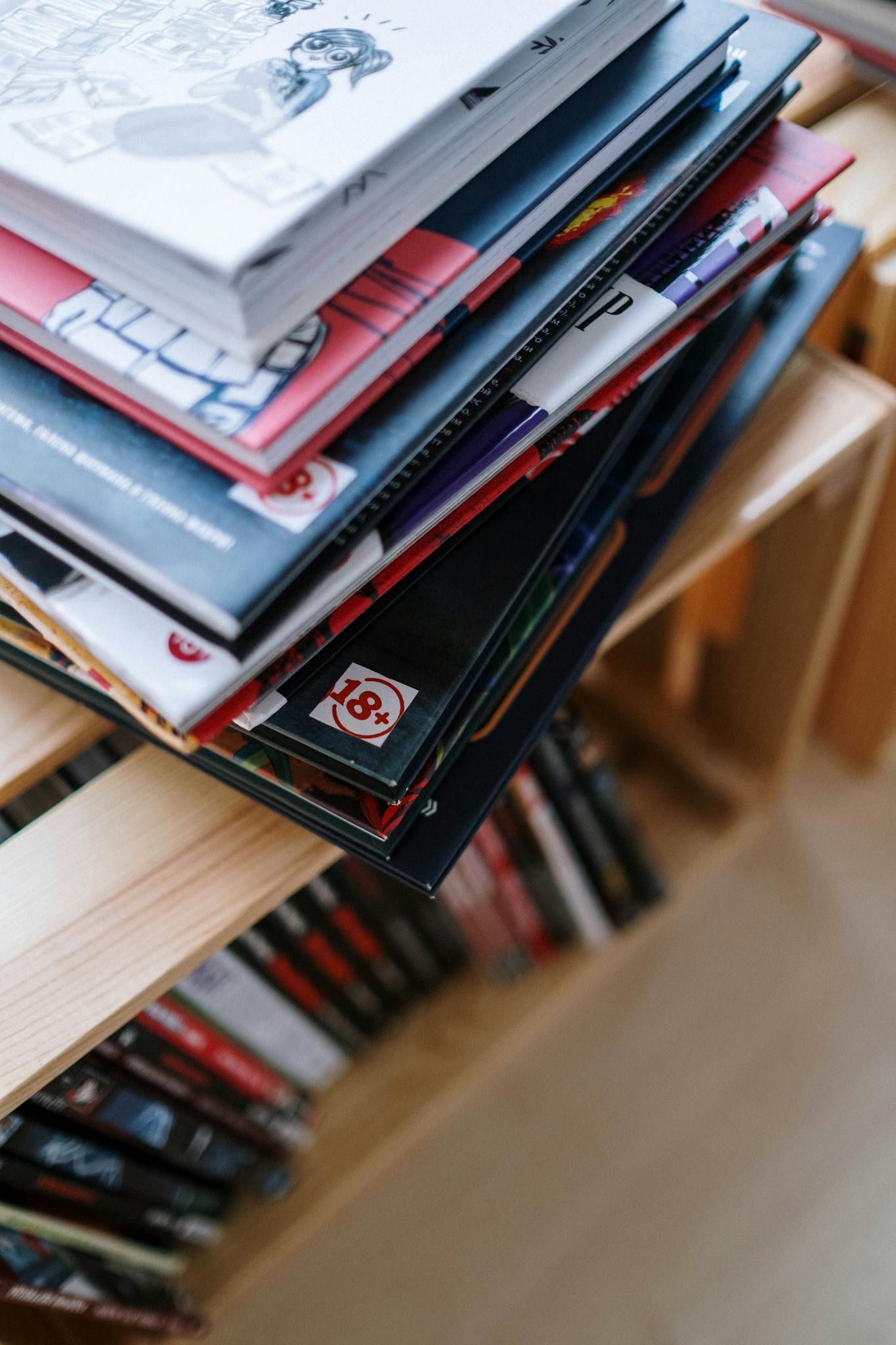 A close-up view of a stack of comics placed on a bookshelf, emphasizing colorful covers and organization.